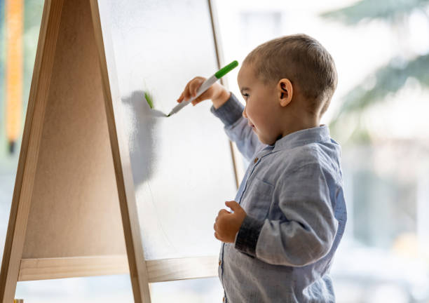 istock Toddler Boy Drawing Pictures On White Board 1308451600