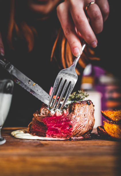 istock woman hands with fork and knife eating beef steak in cafe 1308452088