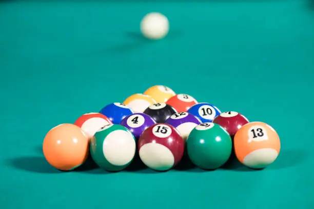 Image of fifteen billiard balls ready to play on the green pool table