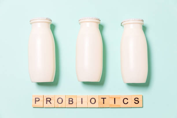 istock Small bottles with probiotics and prebiotics dairy drink on blue background. Production with biologically active additives. Fermentation and diet healthy food. Bio yogurt with useful microorganisms 1308455341