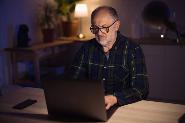 istock Mature freelancer using laptop from home at night 1308455364