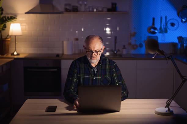 istock Mature freelancer using laptop from home at night 1308455387