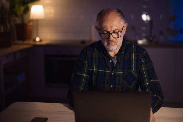 istock Mature freelancer using laptop from home at night 1308455429