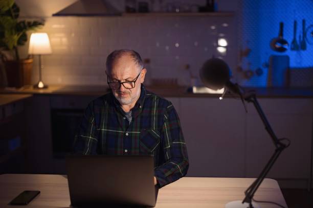 istock Mature freelancer using laptop from home at night 1308455485