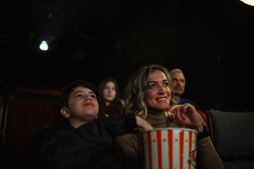 Mom is taking her son to watch a movie or a theatre play. They are laughing and spending a fun time together.