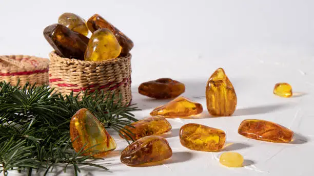 Photo of Variety of magical sparkling amber stones on a white plastered surface. Material for jewelers.