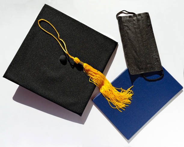 istock Graduate black cap, blue diploma and protective face mask on white background, protection from the virus while studying, new normality 1308458137