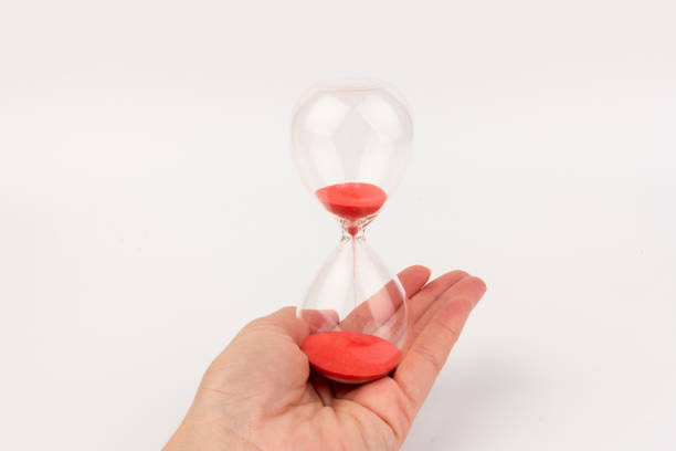 istock Hand holding a hourglass isolated on white background 1308459502