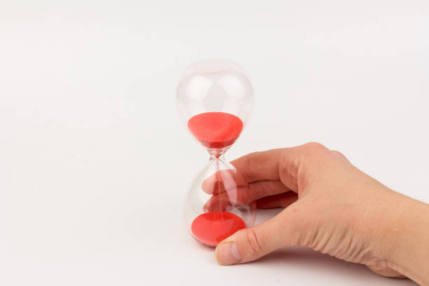 istock Hand holding a hourglass isolated on white background 1308459564
