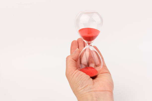 istock Hand holding a hourglass isolated on white background 1308459604
