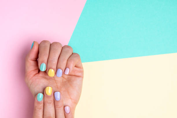 mãos com esmalte pastel em fundo multicolorido. - unha - fotografias e filmes do acervo