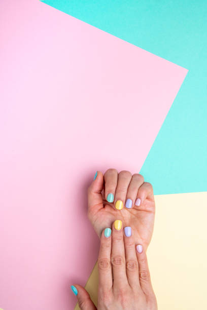 istock Hands with pastel nail polish on multicolored background. 1308463632