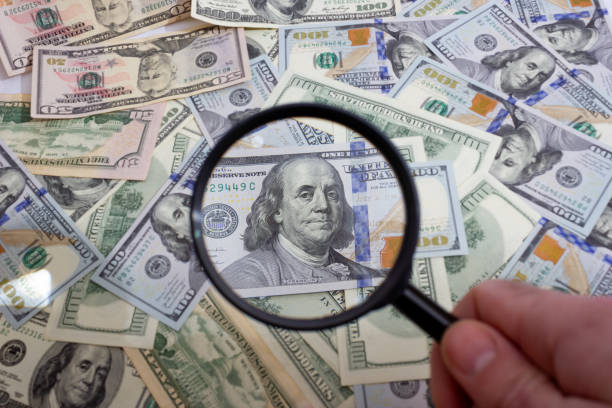 istock Magnifying glass on the background of bundle dollars - texture, background 1308469686