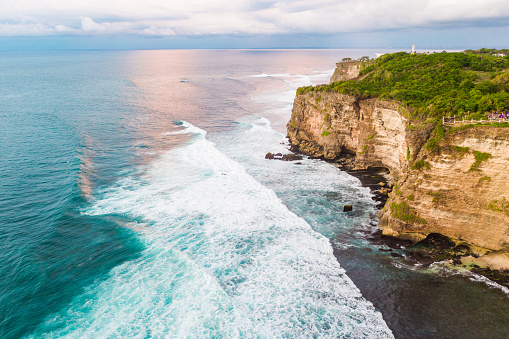 Bali rocky shores on the south Bukit. Ocean waves crashing onto sharp high cliffs. View from above.