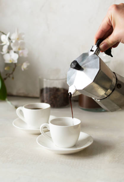 Coffee is poured from the geyser coffee maker into the espresso cup. stock photo
