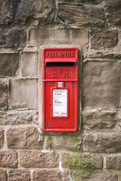 Hardwick, Derbyshire - 22 March 2021 - Red Royal Mail letter post box in old historic dry stone wall rural location.