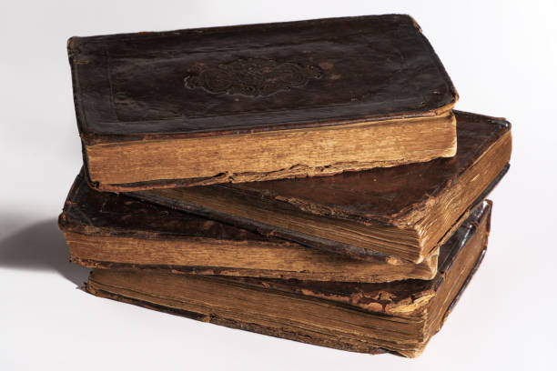 istock Stack of old worn out leather-bound books isolated on white background. Closeup. 1308478350