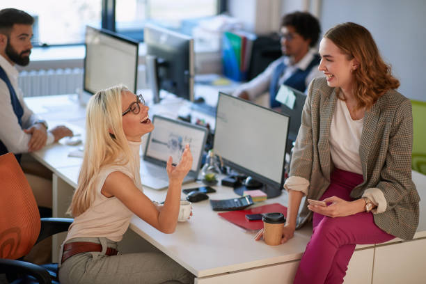 istock female colleagues talking and smiling at work in modern open space office, with  male colleagues in the background. casual, open space, modern, office, business concept 1308478587