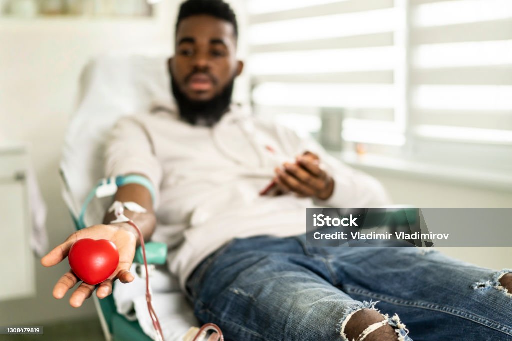 An african-american young man donating blood in the hospital African-American man is happy to donate blood for charity Blood Donation Stock Photo