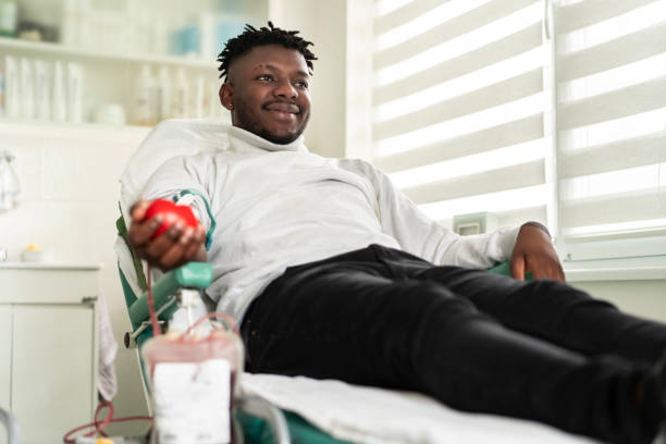 An african-american young man donating blood in the hospital African-American man is happy to donate blood for charity blood bank stock pictures, royalty-free photos & images