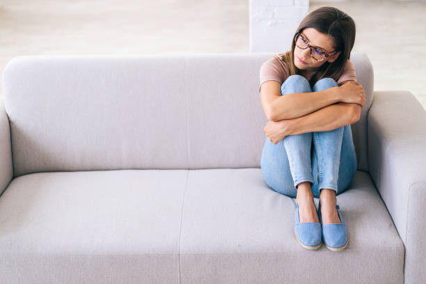 istock Sad woman sitting on a sofa at home 1308483234