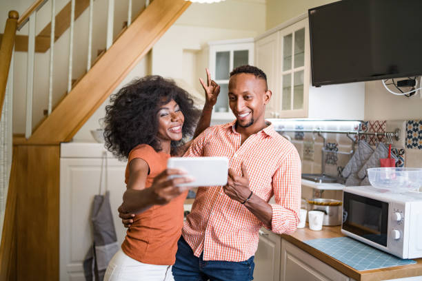 istock Young couple in the kitchen room drinking coffee and taking selfie 1308483258