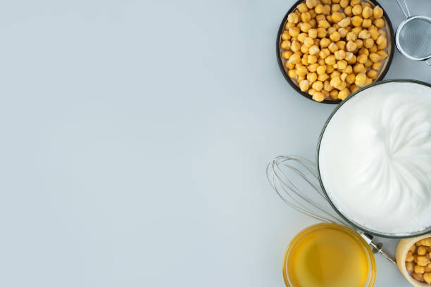 istock Chickpea aquafaba. Egg replacement. Vegan cooking concept. whipped chickpeas liquid in glass bowl. chickpea in a ceramic plate. whisk. gray isolated background. Top view. Copy space. Banner 1308483551