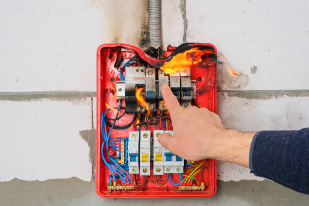 istock Male hand turns off burning switchboard from overload or short circuit on wall 1308487199