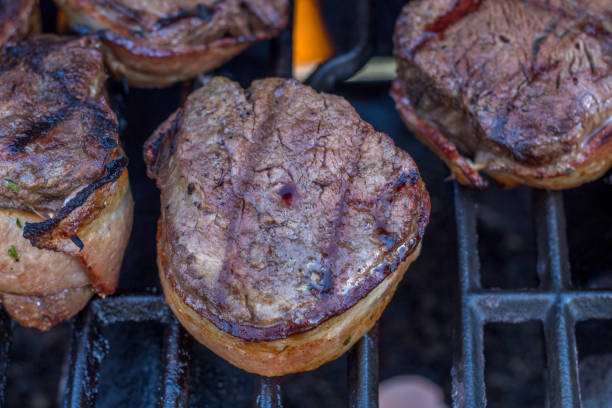 istock Juicy bacon wrapped filet mignon steaks on barbeque grill with flames. 1308488861