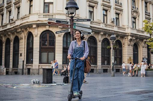 Young woman is driving an electric scooter while going to work