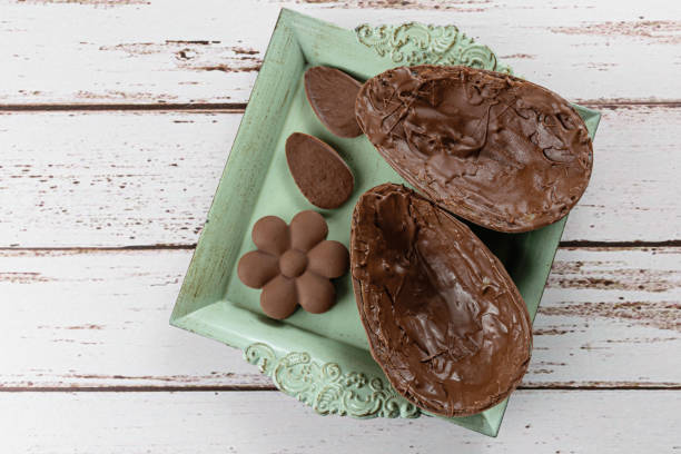 istock Two halves of chocolate Easter egg, on a small old tray. Next to mini chocolates (top view). 1308493477