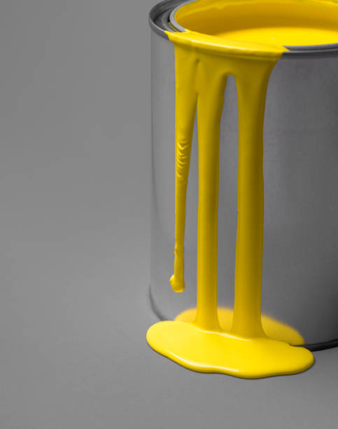 istock Yellow paint dripping from a metal tin can. Paint puddle close-up. 1308494806