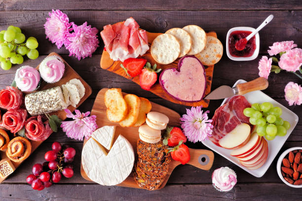 Mother's Day charcuterie table with a dark wood background. Assorted cheese, meat, fruit and sweet appetizers. Mother's Day theme charcuterie table scene against a dark wood background. Assorted cheese, meat, fruit and sweet appetizers. Top down view. appetizer plate stock pictures, royalty-free photos & images