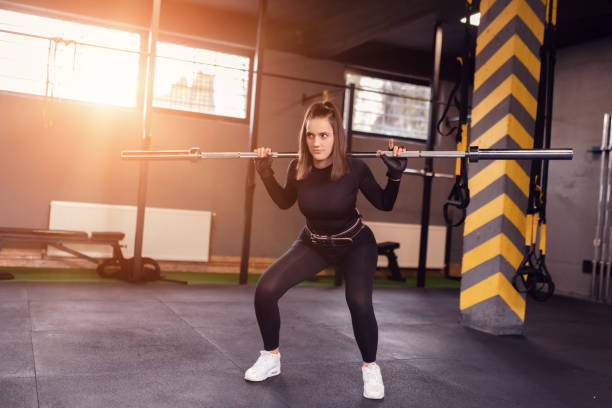 istock sporty girl squats with barbell training. 1308498951