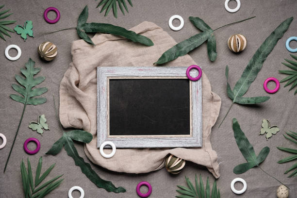 Jungle floral flat lay on earth-colored natural linen textile. Blackboard, chalk board, copy-space. Tropical plants, exotic fern, palm leaves. Lush greenery, quail feathers, dry lime fruit, wood rings el piso floral de la selva yacía sobre el textil de lino natural de color tierra. pizarra, pizarra, espacio de texto. plantas tropicales, helecho exótico, hojas de palma. vegetación exuberante, plumas de codorniz, fruta de lima seca, anillos de madera