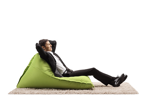 Businessman relaxing on a green bean bag chair isolated on white background