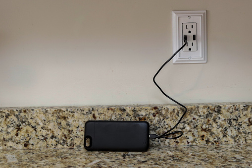 A cellphone charging phone case being charge on a wall outlet