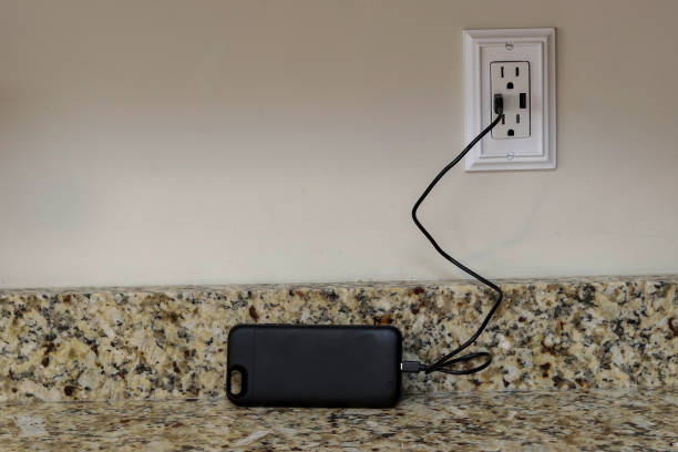 A cellphone charging phone case being charge on a wall outlet stock photo