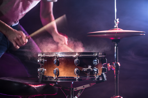 The drummer plays the drums. Beautiful blue and red background, with rays of light. Beautiful special effects smoke and lighting. The process of playing a musical instrument. The concept of music.