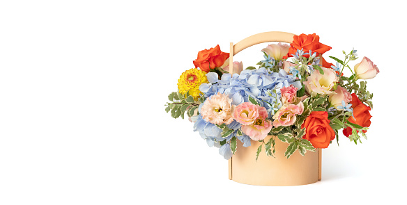 Bouquet of flowers in a wooden basket isolated on a white background. Spring flowers. Roses, eustoma, hydrangea composition. Copy space.