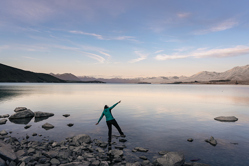 Woman balancing on the lakeside of Tekapo. Canterbury Region, New Zealand.