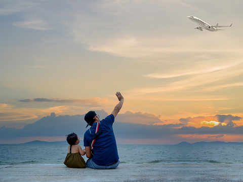 Dad sitting together with kid on the beach. Asian family lifestyle. Travel and relaxing on summer holiday