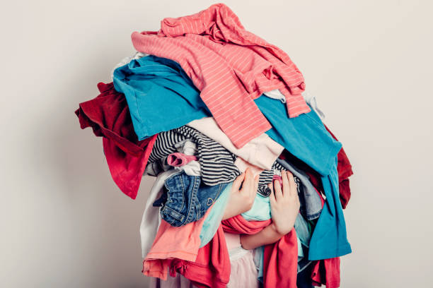 мама маленький помощник. милая кавказская девушка сортирует одежду. очаровательный забавный ребенок организации органазирования одежды. � - washing стоковые фото и изображения