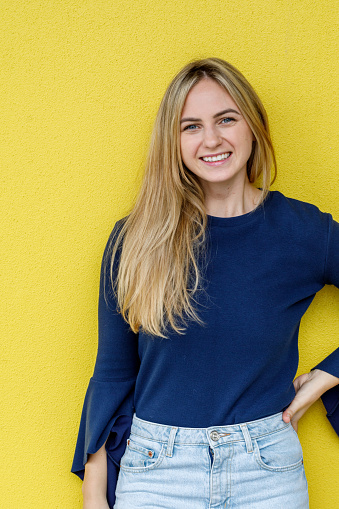 Happy Young Australian Woman Leaning Against Yellow Wall In Urban Location