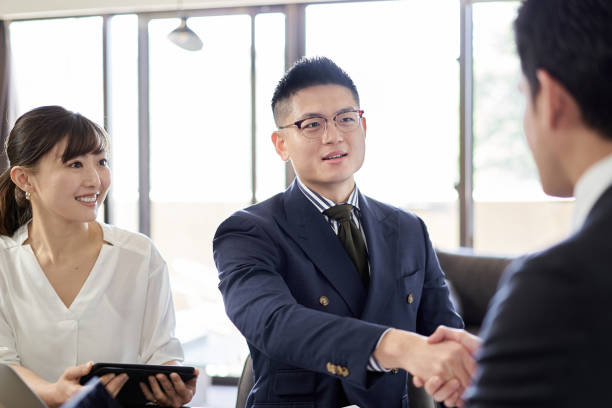 Asian businessman shaking hands with client Asian businessman shaking hands with client coalition photos stock pictures, royalty-free photos & images