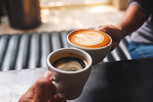 istock a man and a woman clinking white coffee mugs in cafe 1308540716