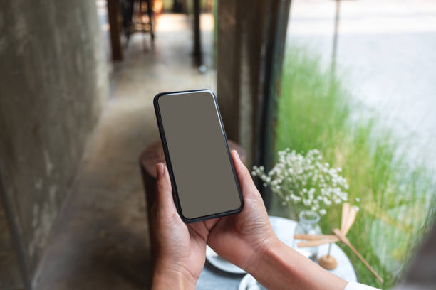 istock a woman holding mobile phone with blank desktop screen in cafe 1308540772