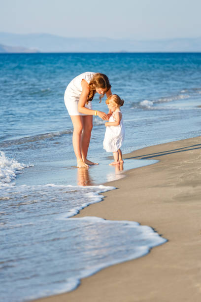 istock Mother and daughter walking on the beach 1308542735