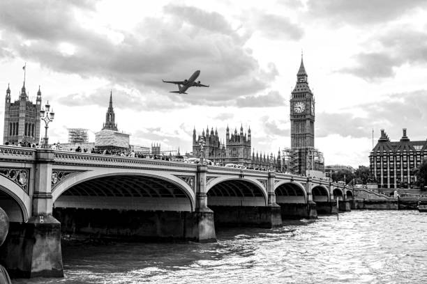 One of the famous bridges that crosses the River Thames in London, United Kingdom, with a passenger aircraft flying overhead.