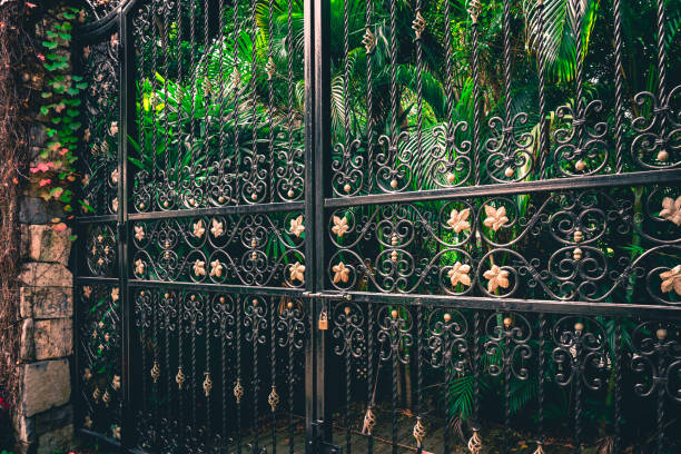 Metal fence against the sunset background. Fence and concrete ornate fence of a public park, behind the fence trees and sunset. Fencing the plot is not obligatory, but it easily defines its boundaries and increases the sense of security and privacy.